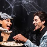 Drei verkleidete Partygäste teilen sich Popcorn auf einer Halloweenfeier.