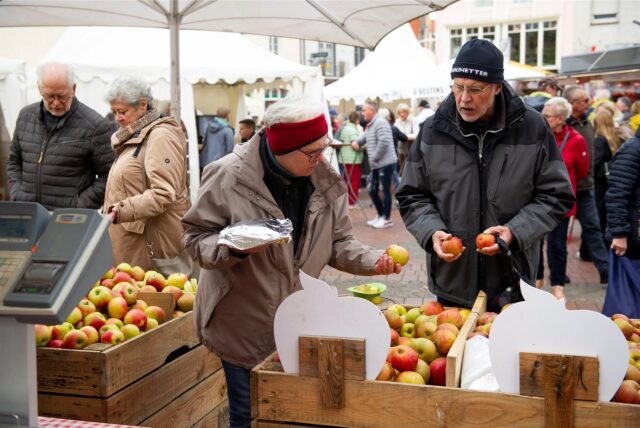 Ein Ehepaar steht beim Gänsemarkt in Haltern an einem Marktstand, an dem Äpfel angeboten werden.
