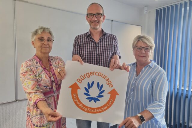 Zwei Frauen und ein Mann halten ein Plakat für den Bürgercourage-Preis hoch.