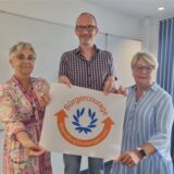 Zwei Frauen und ein Mann halten ein Plakat für den Bürgercourage-Preis hoch.