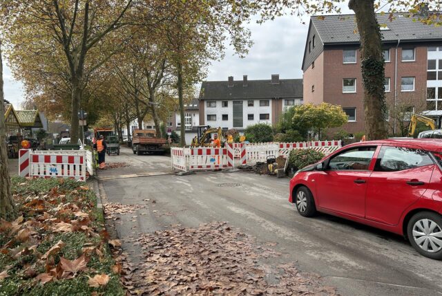 Absperrungen neben und teilweise auf der Straße, ein Auto wartet, um durchfahren zu können.