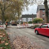 Absperrungen neben und teilweise auf der Straße, ein Auto wartet, um durchfahren zu können.