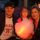 Eine verkleidete Familie lächelt in die Kamera. Das Mädchen hält Zuckerwatte in den Händen.