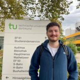 Der Maschinenbaustudent Malte steht vor einer Ausschilderung der Technischen Universität in Dortmund