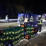 Der Laster liegt im Hintergrund auf der Seite, Bierkästen stapeln sich neben Feuerwehrkräften.