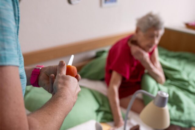 Pflegerin Ramona Rössner schneidet beim ambulanten Besuch ihrer Patientin, der 97-jährigen pflegebedürftigen Seniorin Brigitte Richter, Obst für eine Zwischenmahlzeit.