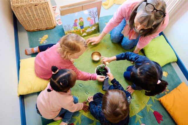 Eine Betreuerin spielt mit Kindern in einer Kita