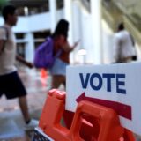 Menschen gehen am ersten Tag der vorzeitigen Stimmabgabe für die US-Wahl an einem Wahlschild vorbei.