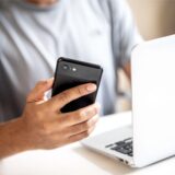 Hand mit Handy und Laptop in Nahaufnahme