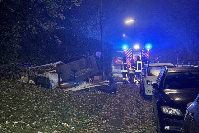 Mobiliar und Unrat, davor ein Feuerwehrfahrzeug hinter parkenden Autos.