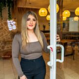 Sibel Cömlek steht in ihrem Café „Brunch & Cake“ in der Hertener Innenstadt und hält mit der linken Hand die Tür auf.