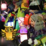 Kinder halten an Sankt Martin bei einem Martinsumzug ihre bunten Laternen.