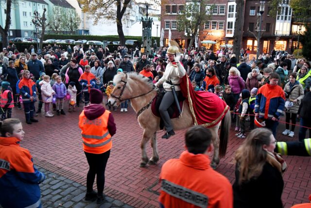 Eine als St. Martin gekleidete Frau reitet auf einem Pferd, daneben viele Kinder aus Hertener Kitas.