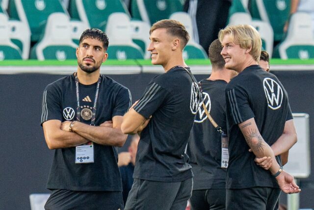 Emre Can, Nico Schlotterbeck und Julian Brandt stehen in einem Stadion.
