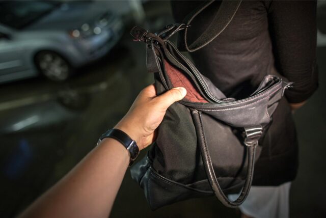 Symbolbild: Eine Person greift nach der Handtasche einer anderen Person.