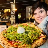 Redakteurin Jessica Will mit einer Pizza, belegt mit viel Rucola und Burratta.