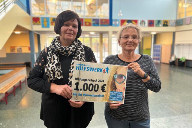 Maren Zäuner und Rosie Uysal nehmen den Bildungs-Scheck von Lensing Media in der Hans-Christian-Andersen-Schule entgegen.