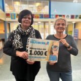 Maren Zäuner und Rosie Uysal nehmen den Bildungs-Scheck von Lensing Media in der Hans-Christian-Andersen-Schule entgegen.