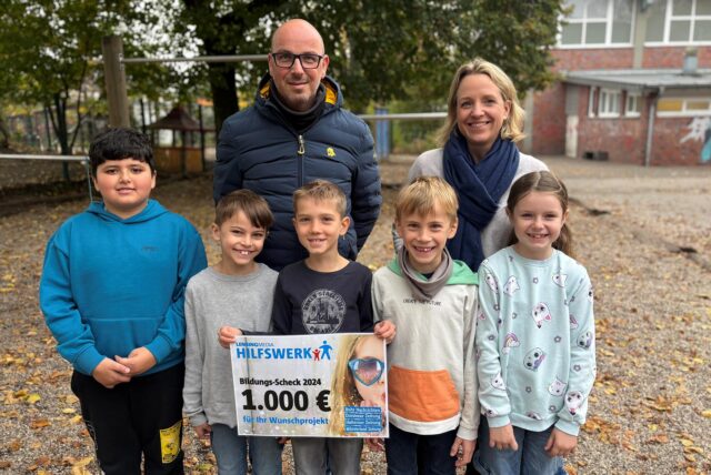 Anne Kemper, Sven Krambeer und fünf Schüler der Marktschule Ickern nehmen den Scheck des Lensing-Media-Hilfswerkens entgegen