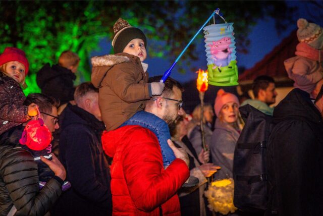 Kinder mit Laternen auf den Schultern von Erwachsenen beim Sankt Martin Fest auf Gut Königsmühle in Dortmund.