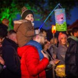 Kinder mit Laternen auf den Schultern von Erwachsenen beim Sankt Martin Fest auf Gut Königsmühle in Dortmund.
