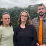 Zwei Mütter und ein Vater von Kita-Kindern aus Brackel stehen in einem Garten in Dortmund und schauen ernst in die Kamera.