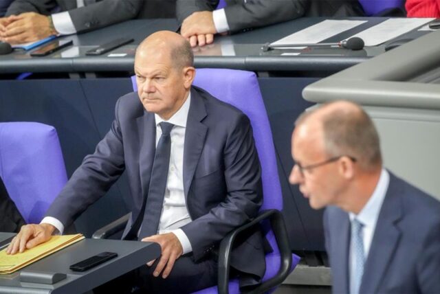 Olaf Scholz sitzt im Bundestag, im Anschnitt Friedrich Merz.