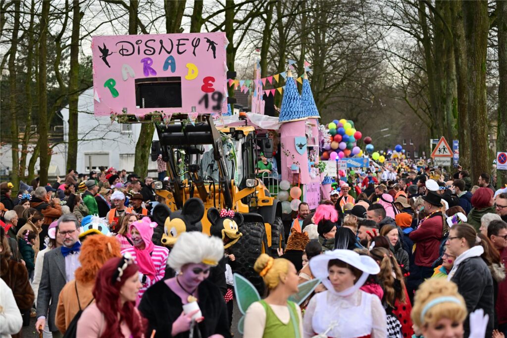 Ein Karnevalswagen und kostümierte Menschen beim Karnevalsumzug. Ein Karnevalswagen und kostümierte Menschen beim Karnevalsumzug.