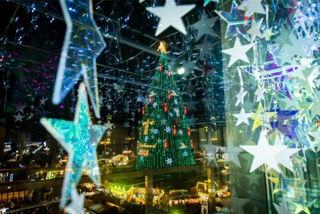 Der leuchtende große Weihnachtsbaum auf dem Weihnachtsmarkt in Dortmund, fotografiert aus dem dekorierten Übergang im Karstadt-Gebäude.