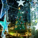 Der leuchtende große Weihnachtsbaum auf dem Weihnachtsmarkt in Dortmund, fotografiert aus dem dekorierten Übergang im Karstadt-Gebäude.