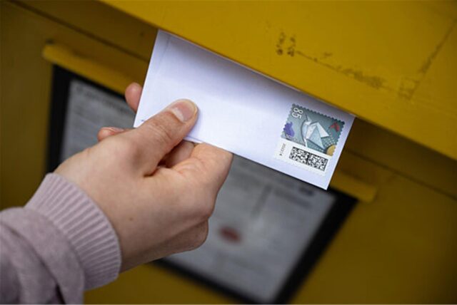 Eine Briefmarke für 85 Cent, die auf einem Brief klebt, wird in einen Briefkasten geworden.