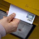 Eine Briefmarke für 85 Cent, die auf einem Brief klebt, wird in einen Briefkasten geworden.