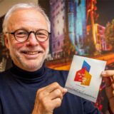 Bürgermeister Matthias Müller steht vor Fotos der ehemaligen Zeche Ewald und hält seine CD „Mein Lied für Herten“ in den Händen.