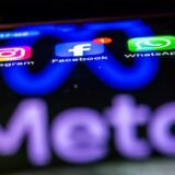 Ein Smartphone, auf dem die Apps Instagram, Facebook und WhatsApp zu sehen sind, mit dem „Meta“-Logo im Hintergrund.