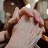 Eine Frau faltet am Buß- und Bettag in der Kirche die Hände zum Gebet.