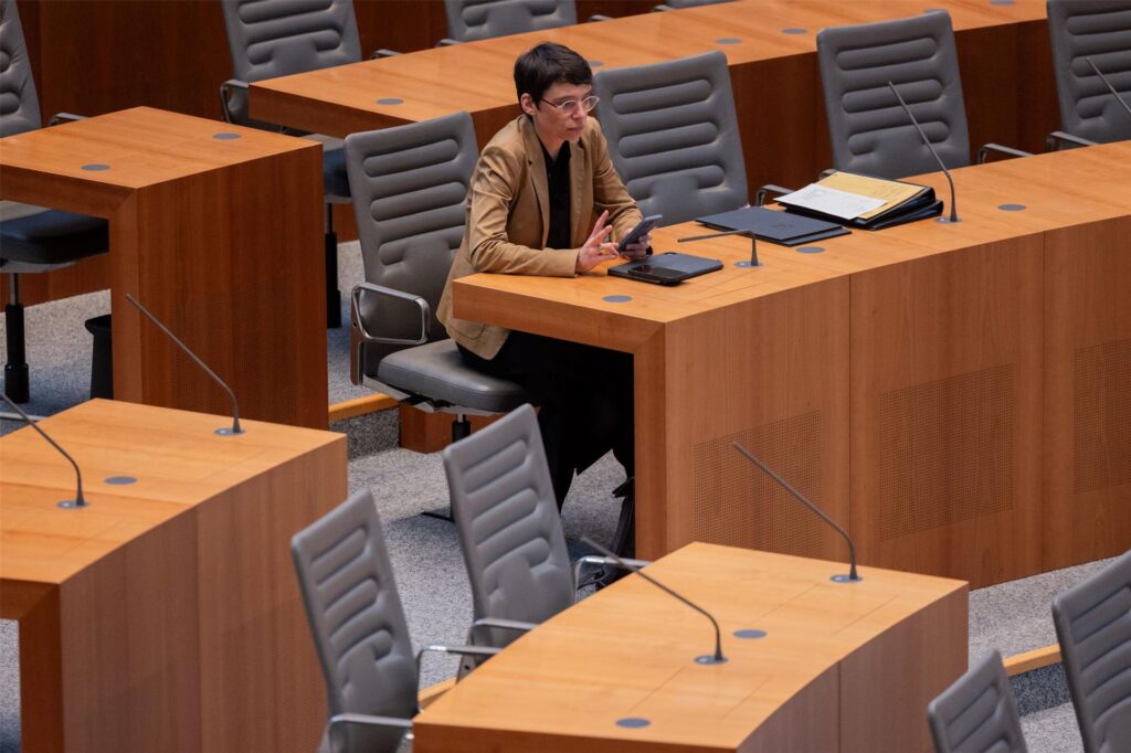 Josefine Paul sitzt im Plenum des Landtags an einem Tisch und schaut in ihr Handy. Josefine Paul sitzt im Plenum des Landtags an einem Tisch und schaut in ihr Handy.
