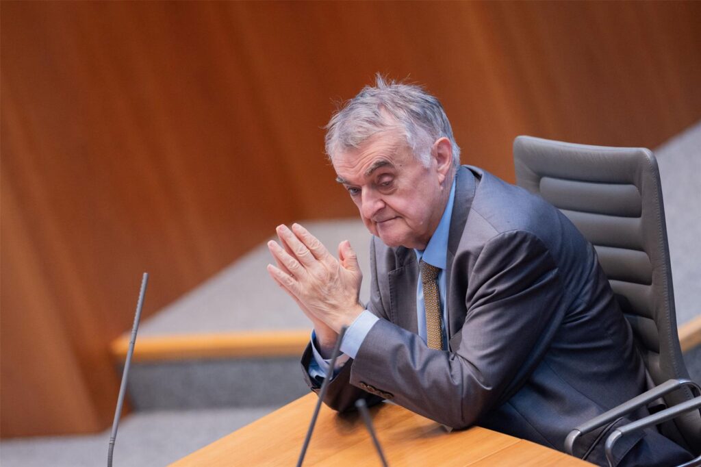 Herbert Reul sitzt in einem Anzug an einem Tisch und hat die Handflächen aneinander gelegt. Herbert Reul sitzt in einem Anzug an einem Tisch und hat die Handflächen aneinander gelegt.