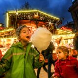 Ein Junge steht neben einem kleinen Mädchen auf dem Dortmunder Weihnachtsmarkt. Beide halten eine große Zuckerwatte in der Hand, der Junge hält außerdem ein Lebkuchenherz in die Kamera.