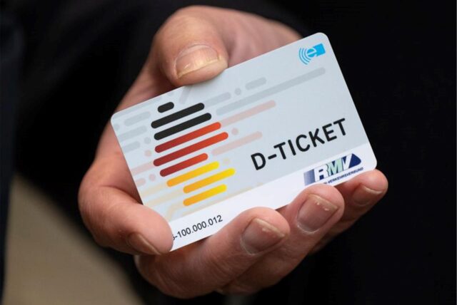 Eine Hand hält ein Deutschlandticket.