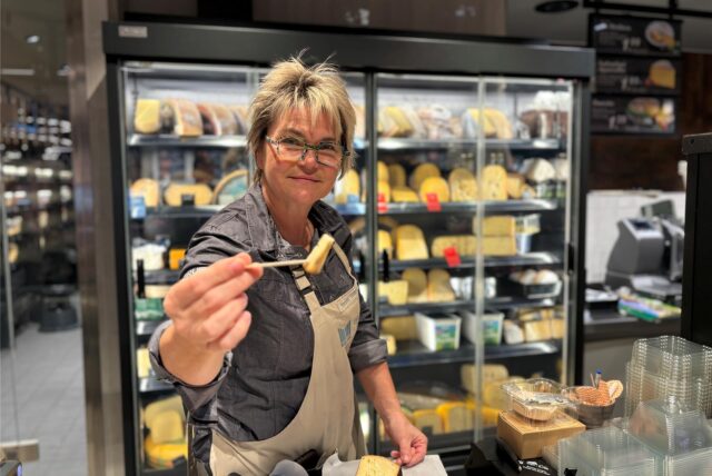 Kerstin Schlieker hält im neuen Marktkauf in Dortmund-Aplerbeck einen Käse zum Probieren über die Theke.