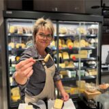 Kerstin Schlieker hält im neuen Marktkauf in Dortmund-Aplerbeck einen Käse zum Probieren über die Theke.