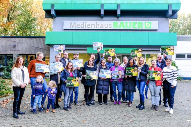 Gruppenbild mit symbolischen Schecks vor dem Medienhaus Bauer in Marl.