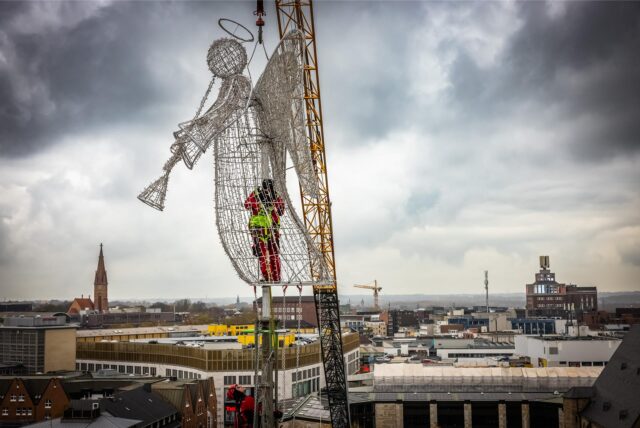 Arbeiter befestigen in luftiger Höhe den Engel auf dem großen Weihnachtsbaum in Dortmund.
