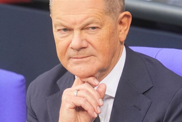 Bundeskanzler Olaf Scholz (SPD) sitzt vor seiner Regierungserklärung im Plenum des Bundestags auf der Regierungsbank.