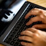 Ein Mann tippt auf einer Tastatur eines Laptops.