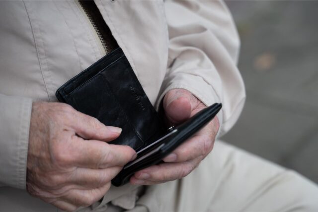 Ein Rentner hält sein Portemonnaie in der Hand. 