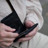Ein Rentner hält sein Portemonnaie in der Hand. 