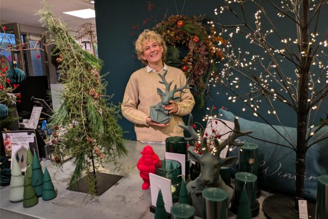 Eine Frau steht vor einer grünen Wand inmitten von Weihnachtsdeko.
