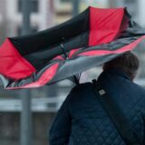 Eine Frau kämpft im Sturm mit ihrem Regenschirm.