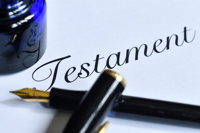 Ein Füllfederhalter und ein Glas Tinte auf einem Blatt mit dem Schriftzug „Testament“.